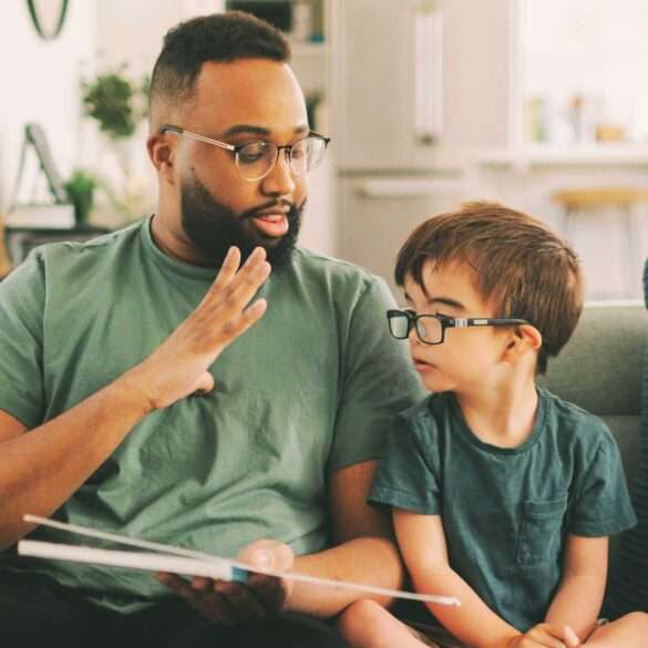 father signs ASL to child with thick glasses