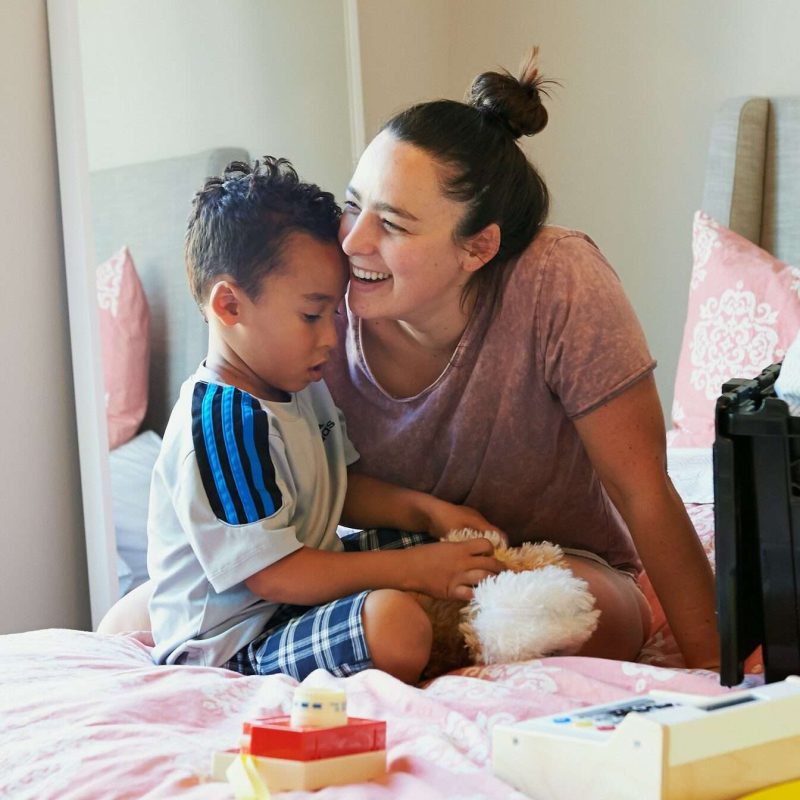 mother and child play with toys on bed